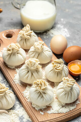Cutting board with raw khinkali with meat, semi-finished products dumplings. cooking khinkali. National Georgian cuisine. vertical image. top view