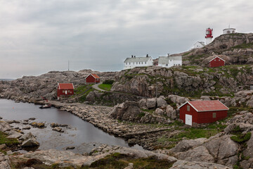 Rocky coast of the sea, traditional red houses and the southern lighthouse Lindesnes fyr Norway