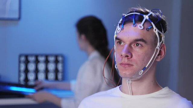 Man wearing EEG topographer for examining brain, doctor making electrogram of scalp activity. Researching of brain work using electroencephalography headset.
