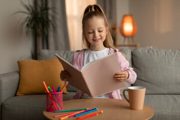 Happy Little Girl Holding Sketch Book Drawing At Home