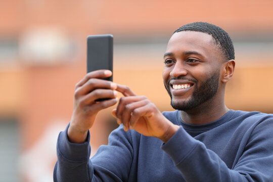 Happy man with black skin taking selfie or photo in the street