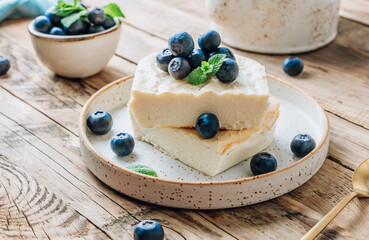 Fresh cottage cheese casserole on white plate on white tile background.