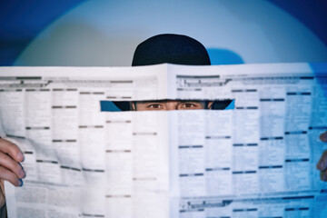 Man hiding watches through the newspaper in the spotlight on studio background - obrazy, fototapety, plakaty
