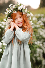 Cute little kid girl 3-4 year old with long curly red hair wear floral wreath and stylish rustic...