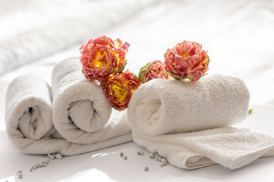 Close-up, white terry bath towels and flowers.