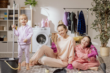 Happy family cleaning house together. Twin sisters helping mommy to tidy up apartment. Portrait of...