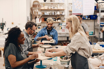 Happy mature instructor teaching student molding clay in art class