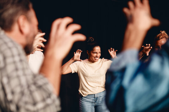 Happy actress gesturing while rehearsing with stage performers in class