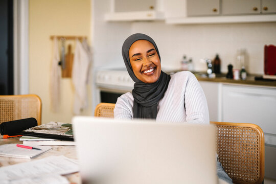 Happy young female freelancer working on laptop at home