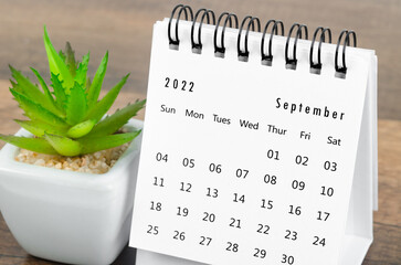 September 2022 desk calendar with plant pot on wooden table.