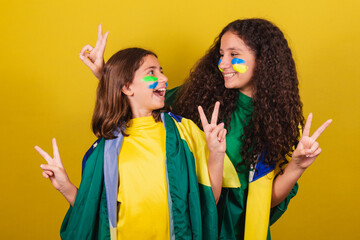 sisters and friends supporters of Brazil, football fans, posing for a photo, fingers of peace and...