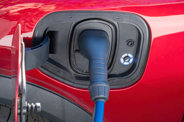 Electric plug charging red sports electric car.