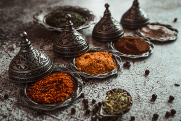 Obraz na płótnie Canvas bright aromatic spices, turmeric, curry, paprika, chili, black pepper, cloves, garlic in a Turkish metal dish