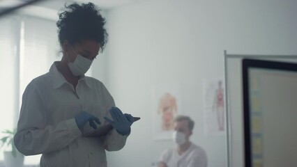Woman doctor writing tablet computer standing office. Medic typing data on pad.