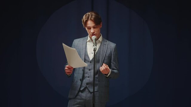 Stand-up cafe, comedy concert. Man telling jokes on stage. Male comedian speaking with audience using microphone, humorous monologue. Mentor coach training.
