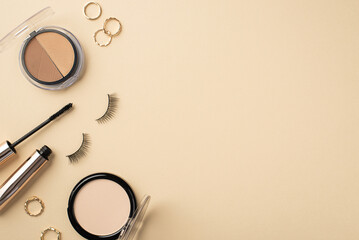 Top view photo of contouring palette gold rings false eyelashes mascara and compact powder on pastel beige background with copyspace