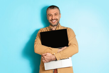 Joyful Middle Aged Man Hugging New Laptop On Blue Background