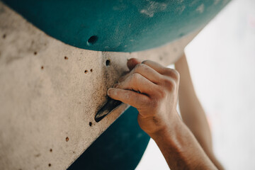 Male hands smeared with magnesium powder grabbing a hold of a climbing wall