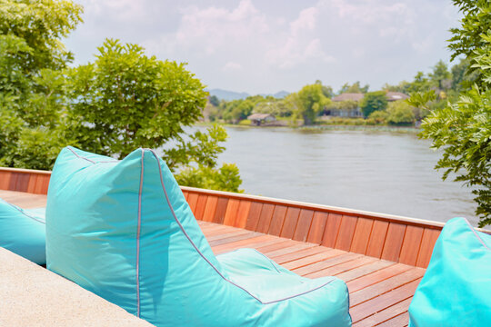 Empty Beach Bean Bag Furniture Blue Color Chair On Wooden Balcony With Lake View And Sky Background In Summer