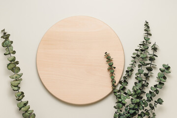 Round wooden podium or stand with eucalyptus leaves top view, display for product and food...