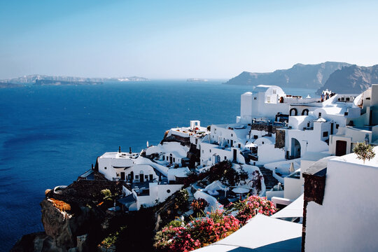 Traditional greek white houses on Santorini coast near the Aegean Sea. Village on the cliff under blue sky.