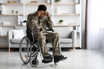 Unhappy black man sitting in wheelchair, wearing military uniform