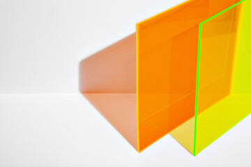 Saturated orange and neon yellow acrylic sheet with long shadow on a bright lit white background....