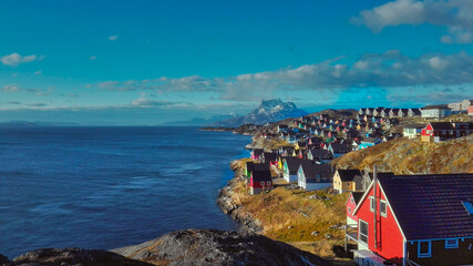 Colorful houses in Nuuk facing a fjord
with mountains in the horizon.