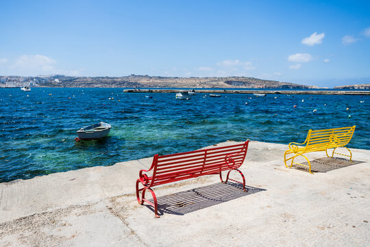 Red and yellow benches face out to sea
