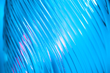Abstract glass background. Texture of wavy glass illuminated with multi-colored light. Pink and blue stains. Close up. Flares on glass.