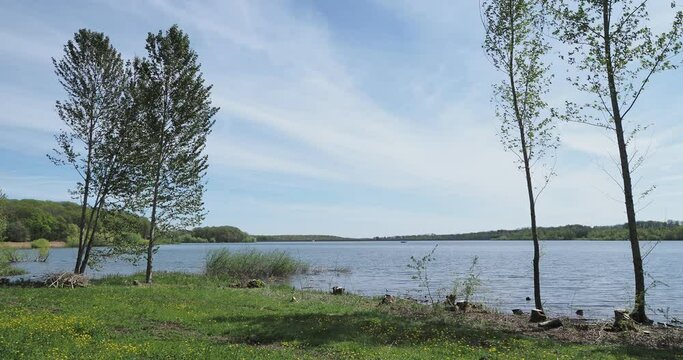 Les eaux calmes du lac de Michelbach dans le Haut-rhin en Alsace. Vue sur la retenue principale et le village depuis le chemin de randonn&eacute;e autour du lac