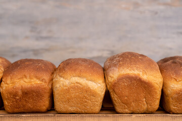 Close-up of freshly baked bread on wooden shelves, front view. Production of bakery products