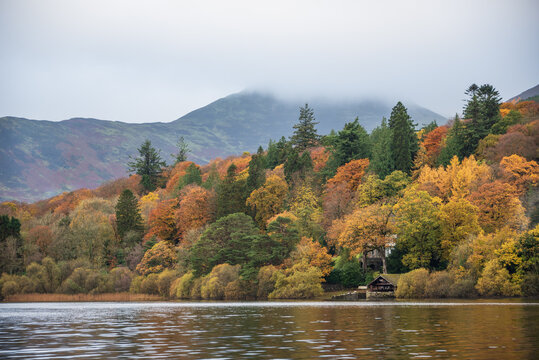 Stunning landscape image of boat house on Derwentwater in Lake District in colorful Autumn forest setting