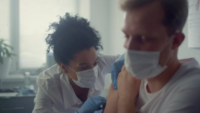 Doctor injecting vaccine patient shoulder in health clinic. Vaccination concept.