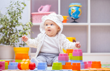 baby girl playing with colourful building blocks at home or kindergarten