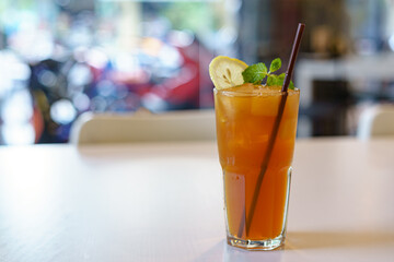 A Glass of Iced tea lemon with brown straw put on the white table.