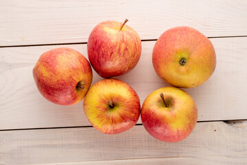 Several red organic apples on a wooden table, close-up, top view.