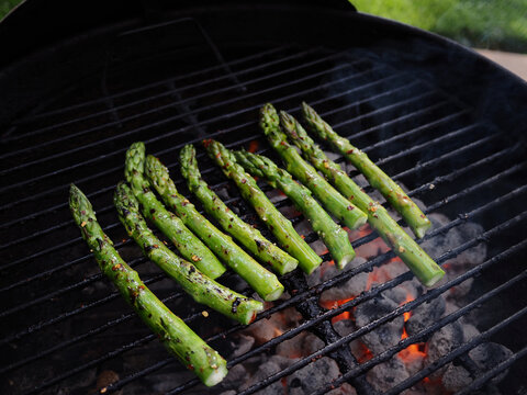 Asparagus being grilled on a hot charcoal barbeque