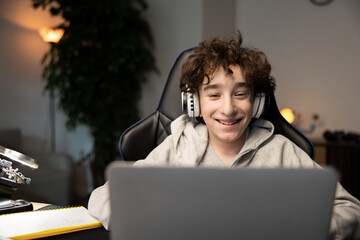 Portrait of happy intelligent young boy smiling at webcam on laptop. Child has remote lessons,...