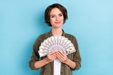 Photo of pretty young short hairstyle lady hold money wear khaki shirt isolated on blue color...