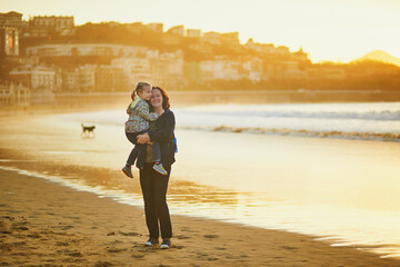 Woman holding little girl on La Concha beach in San Sebastian (Donostia), Basque Country, Spain
