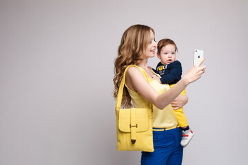 Mother with little child keeping phone and doing selfie