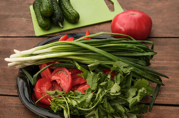 Various raw chopped fresh vegetables with water drops on a wooden table.