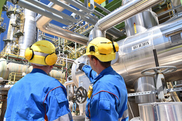 group of industrial workers in a refinery - oil processing equipment and machinery - 503515443