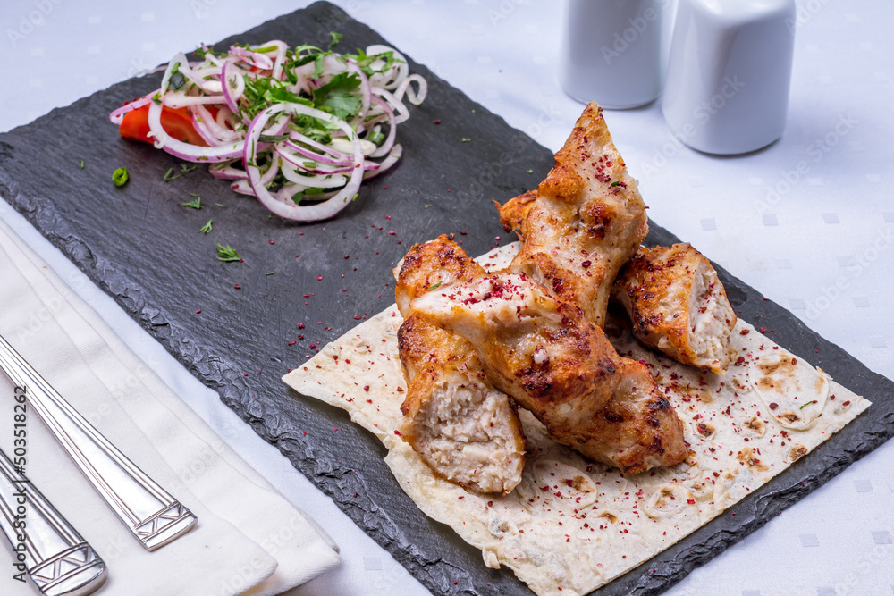 Sticker lula kebab chicken on a black stone plate