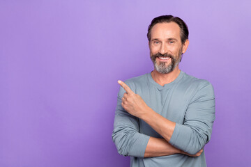 Photo of handsome guy pointing finger empty space promote cool product isolated on violet color background