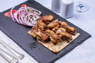 Kebab from lamb ribs on dark stone plate