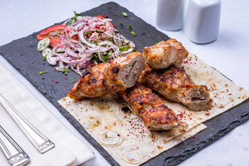 Lula kebab chicken with red onion on dark stone plate