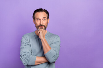 Photo of good looking positive guy look empty space thinking about promoted product isolated on purple color background