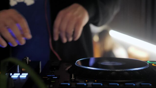 Close up dj hands disc jockey mixing music on his deck with his hands poised over the vinyl record on cd turntable in night club